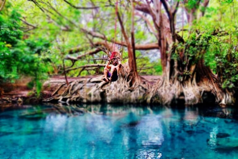 Swimmer on a rope swing above the turquoise Chemka hot spring pool