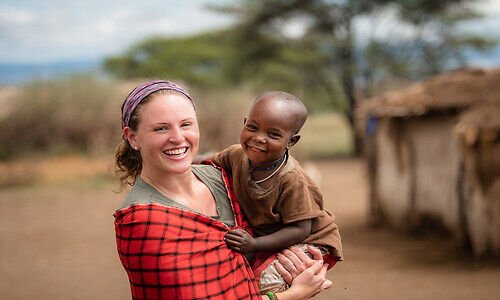 Visitor holding a child during a Maasai village visit