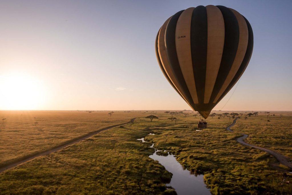 Hot air balloon drifting over the Serengeti plains at sunrise