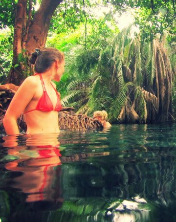 Swimmer standing in the clear turquoise water of Chemka hot springs