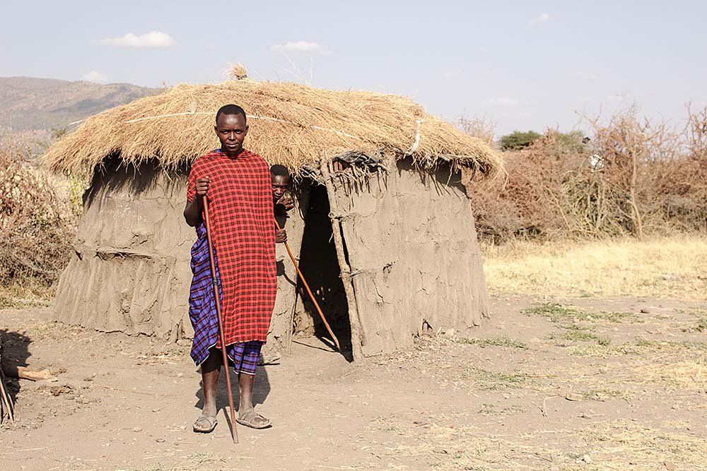 Maasai man standing outside a traditional boma home